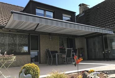 Nahaufnahme des Fensters eines modernen Gebäudes mit einem eleganten, weißen Rollladen, in dem sich das Sonnenlicht spiegelt.